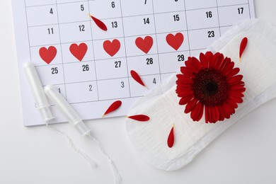 Flat lay composition with calendar and menstrual products on white background