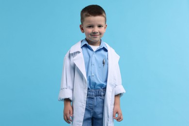 Photo of Little boy pretending to be doctor on light blue background. Dreaming of future profession