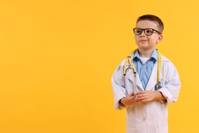 Photo of Little boy with stethoscope pretending to be doctor on yellow background, space for text. Dreaming of future profession