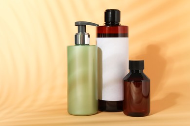 Photo of Shampoo in bottles on pale orange background