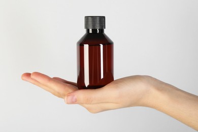 Photo of Woman with shampoo bottle on grey background, closeup