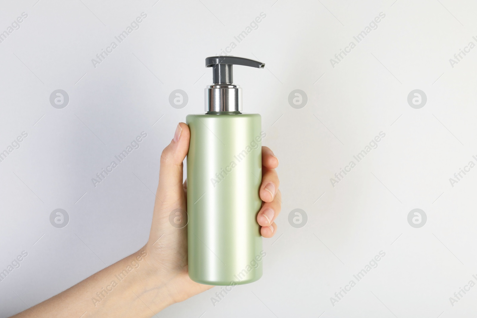 Photo of Woman with shampoo bottle on grey background, closeup