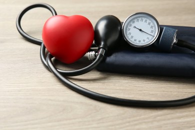 Photo of Blood pressure measuring device and squeeze heart on wooden table