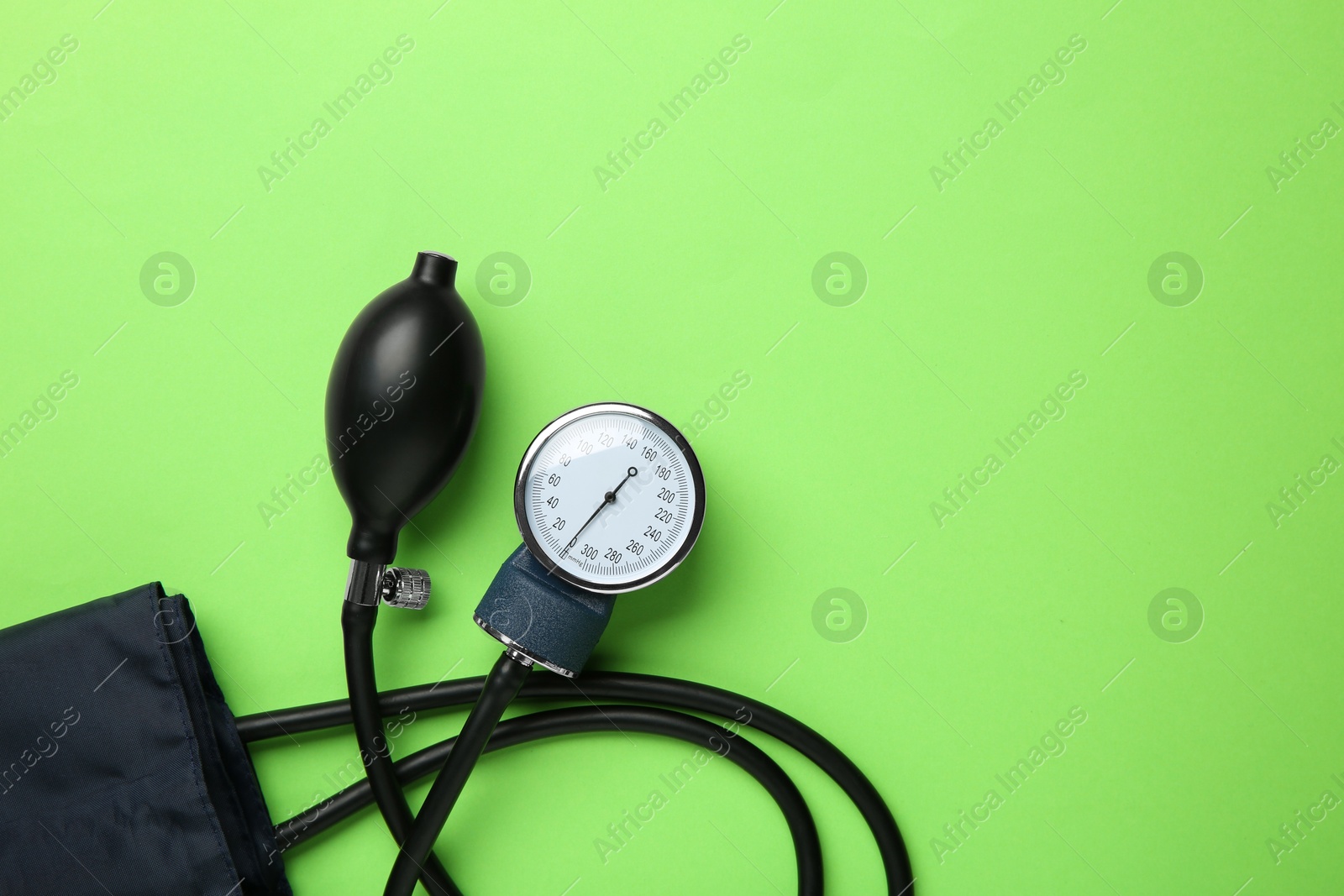 Photo of Blood pressure measuring device on green background, top view. Space for text