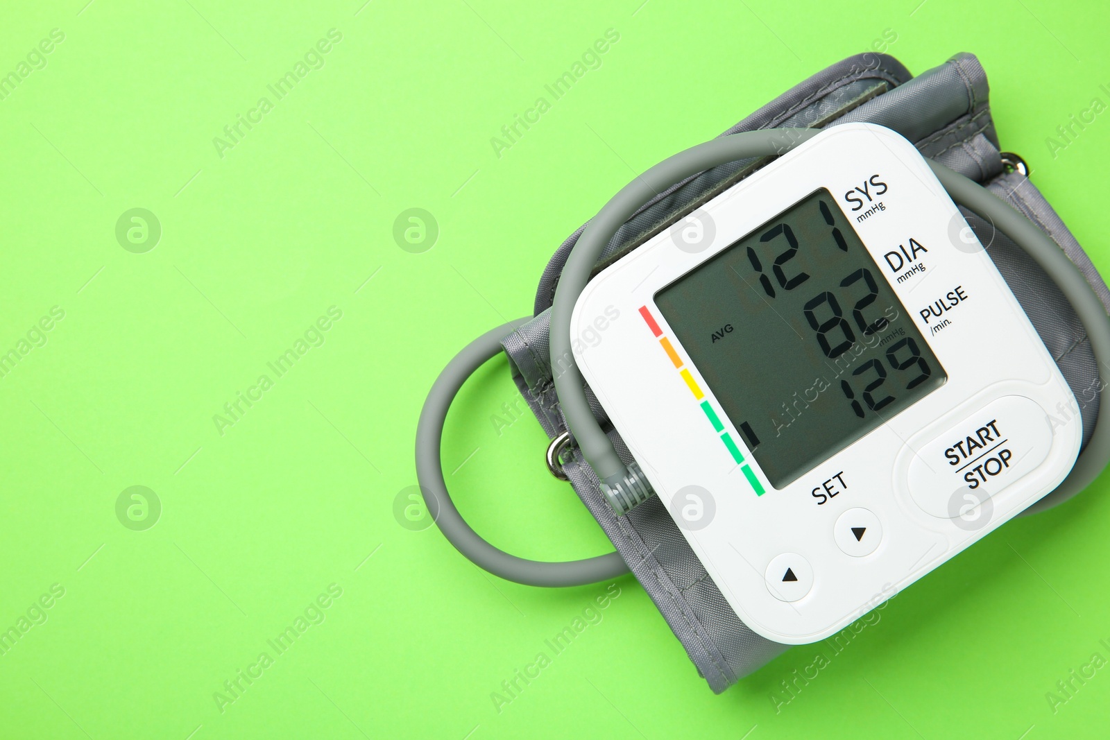 Photo of Blood pressure measuring device on green background, top view. Space for text