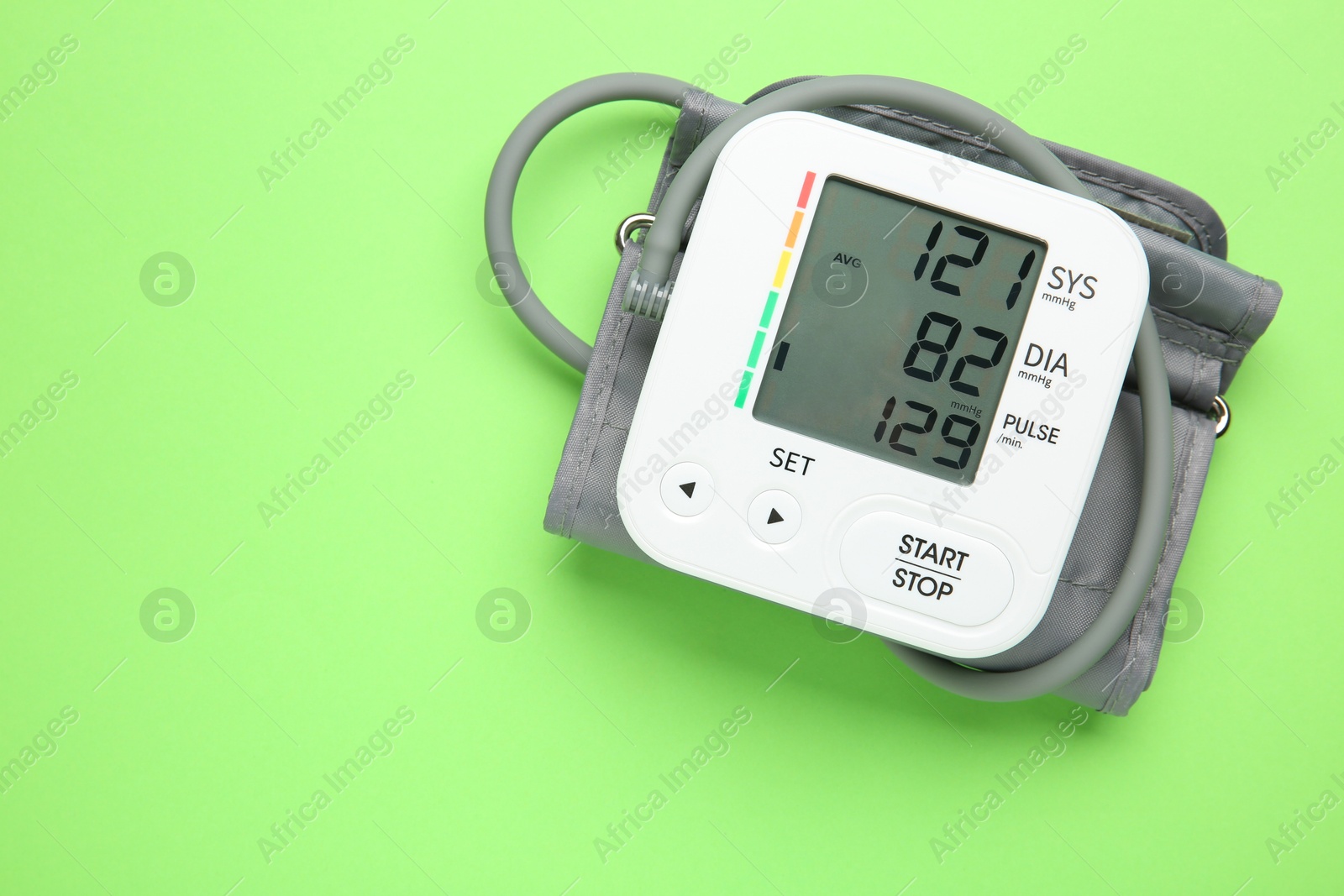 Photo of Blood pressure measuring device on green background, top view. Space for text