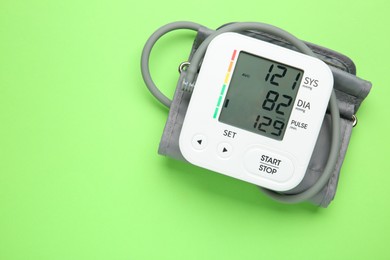 Blood pressure measuring device on green background, top view. Space for text