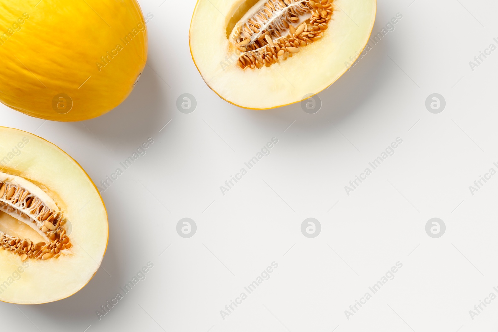 Photo of Fresh whole and cut melons on white background, flat lay. Space for text