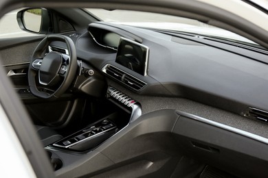 Photo of Steering wheel and dashboard inside of modern luxury car, closeup