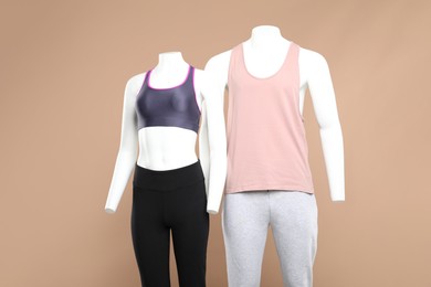 Female and male mannequins with stylish sportswear on beige background