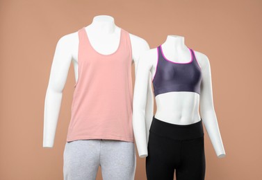 Photo of Female and male mannequins with stylish sportswear on beige background