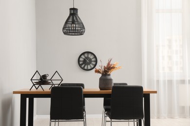 Photo of Wooden table with black chairs in stylish dining room