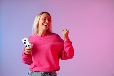 Happy woman with controller on color background, space for text