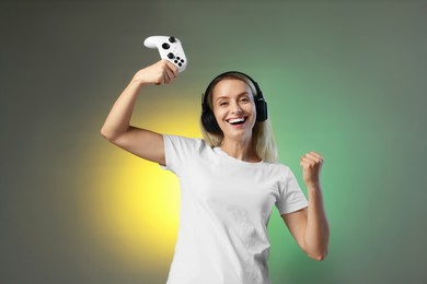 Photo of Happy woman in headphones with controller on color background