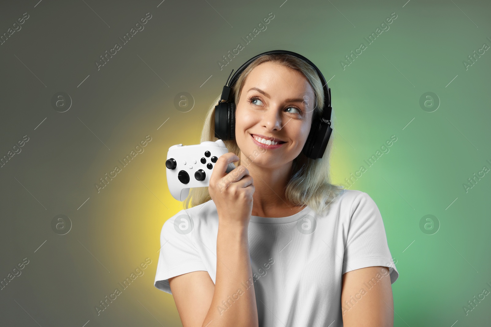 Photo of Happy woman in headphones with controller on color background