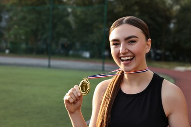 Photo of Happy winner with golden medal at stadium. Space for text