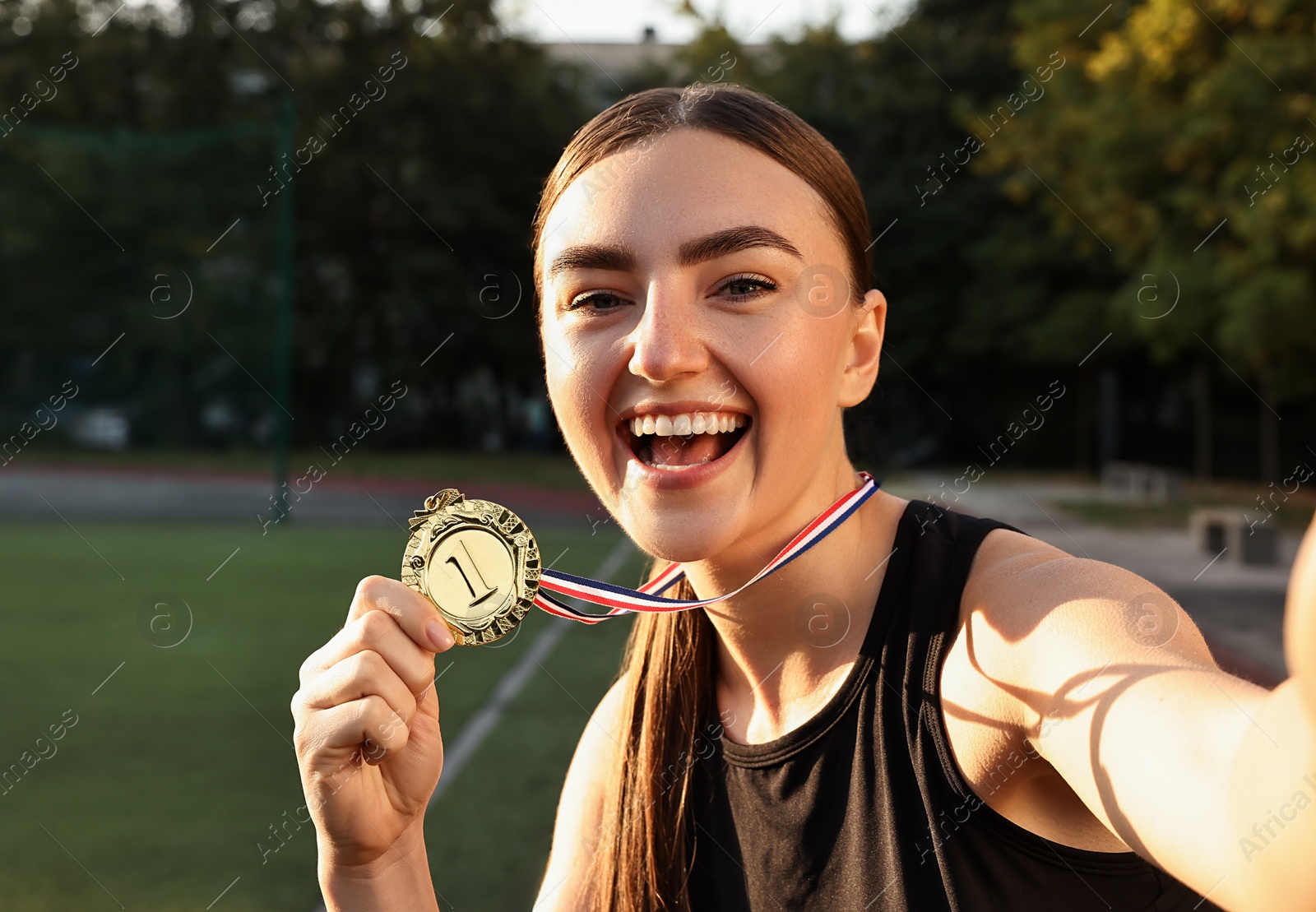 Photo of Happy winner with golden medal taking selfie at stadium