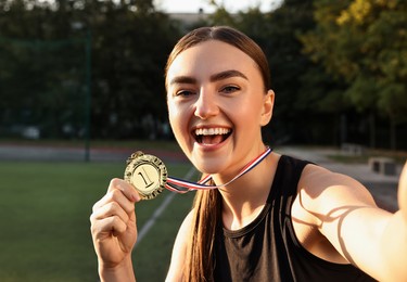 Happy winner with golden medal taking selfie at stadium