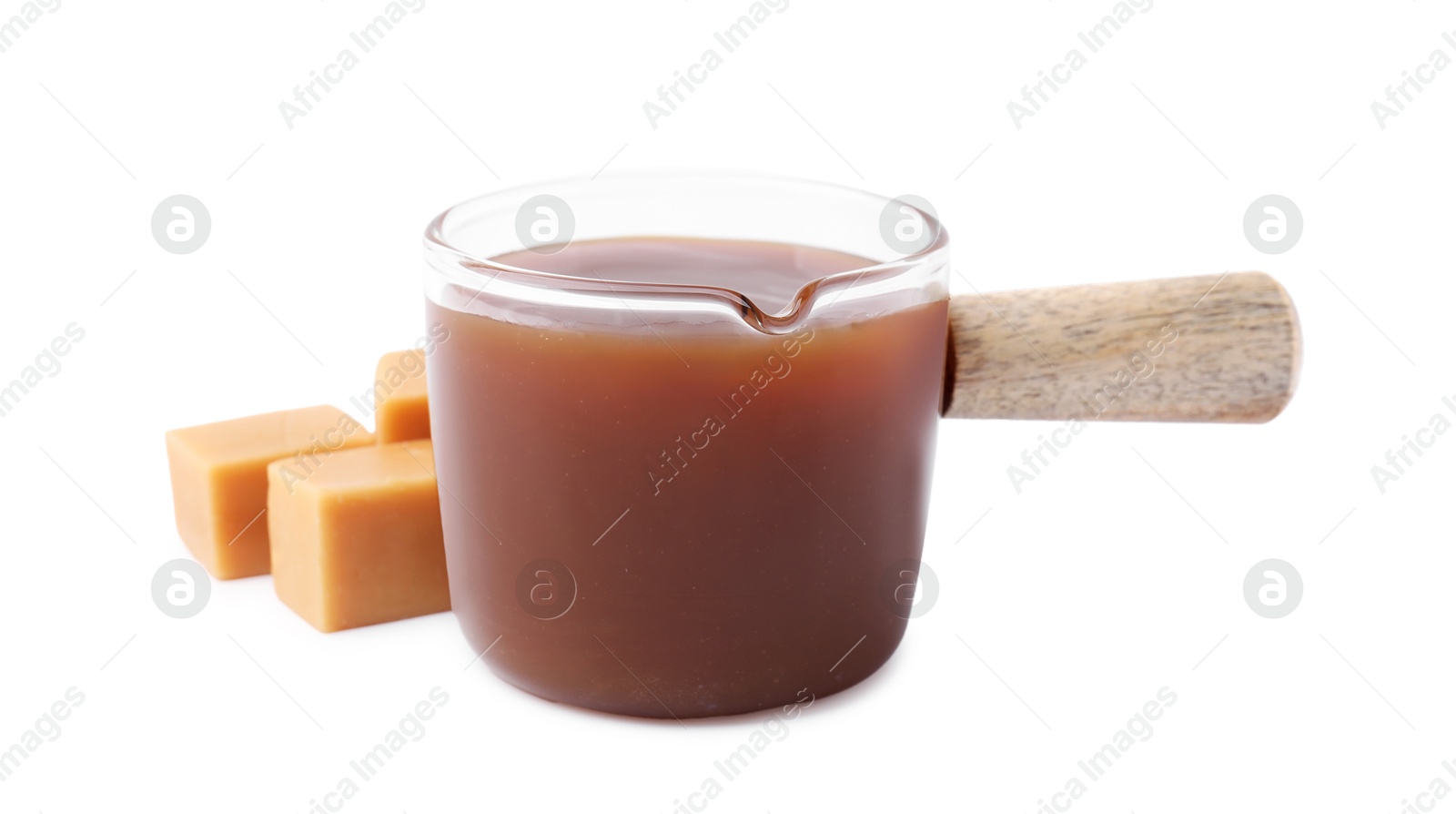 Photo of Tasty caramel sauce in glass measuring cup and sweet candies isolated on white