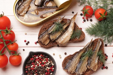 Photo of Delicious sandwiches with sprats and dill served on white wooden table, flat lay