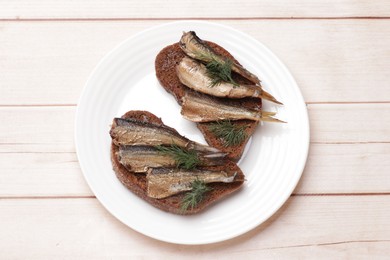 Photo of Delicious sandwich with sprats and dill on white wooden table, top view