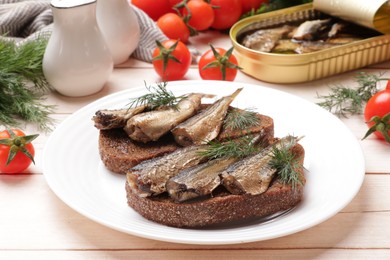 Delicious sandwiches with sprats and dill served on white wooden table, closeup