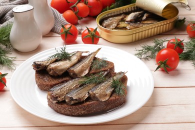 Delicious sandwiches with sprats and dill served on white wooden table, closeup