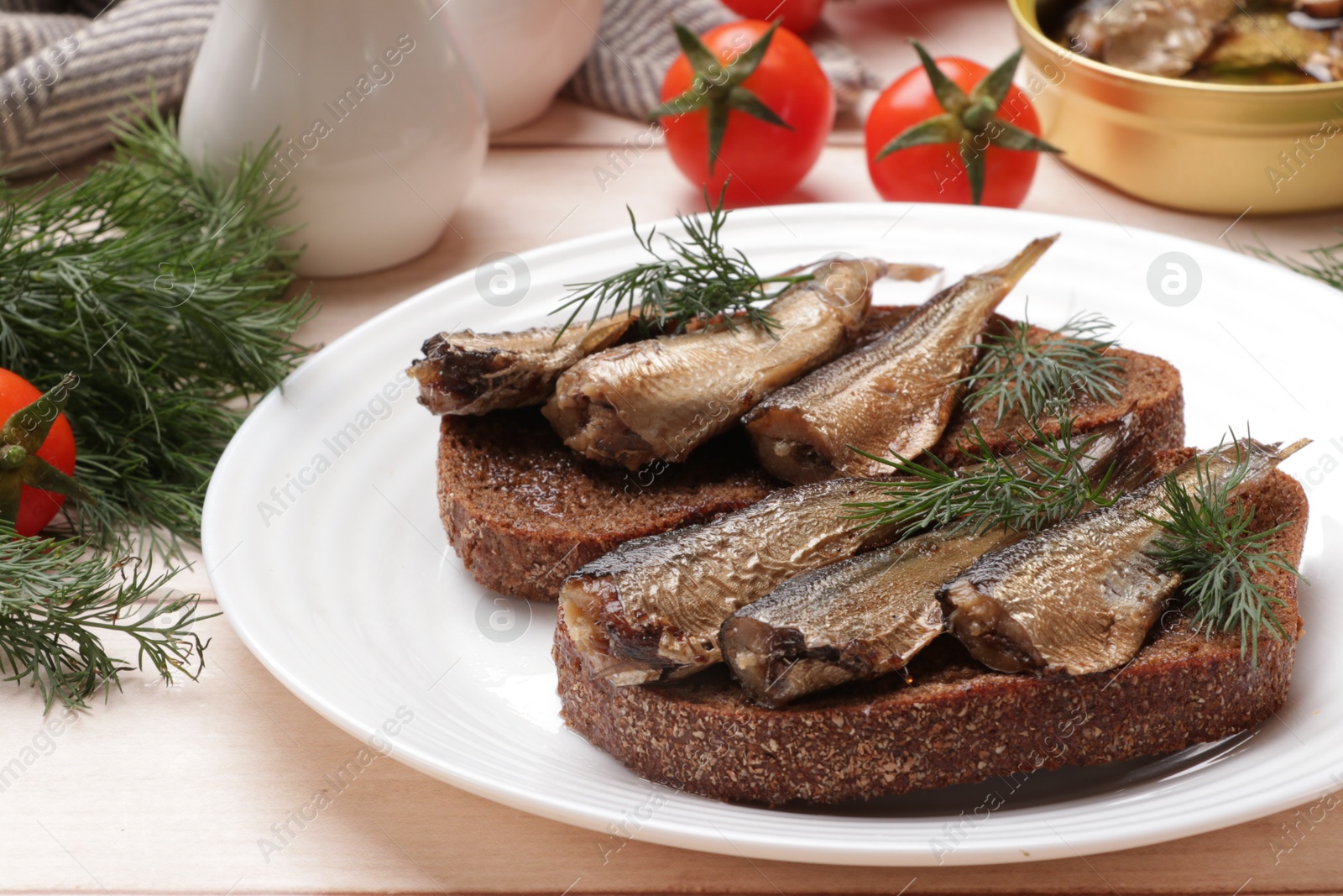 Photo of Delicious sandwiches with sprats, dill and tomatoes on white wooden table, closeup