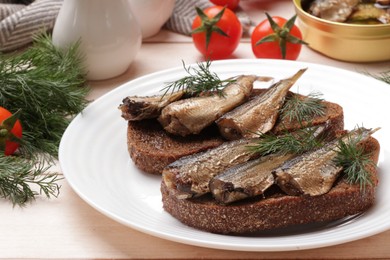 Delicious sandwiches with sprats, dill and tomatoes on white wooden table, closeup