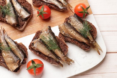 Photo of Delicious sandwiches with sprats, dill and tomatoes on white wooden table, top view