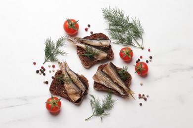 Photo of Delicious sandwiches with sprats, dill, tomatoes and peppercorns on white marble table, flat lay