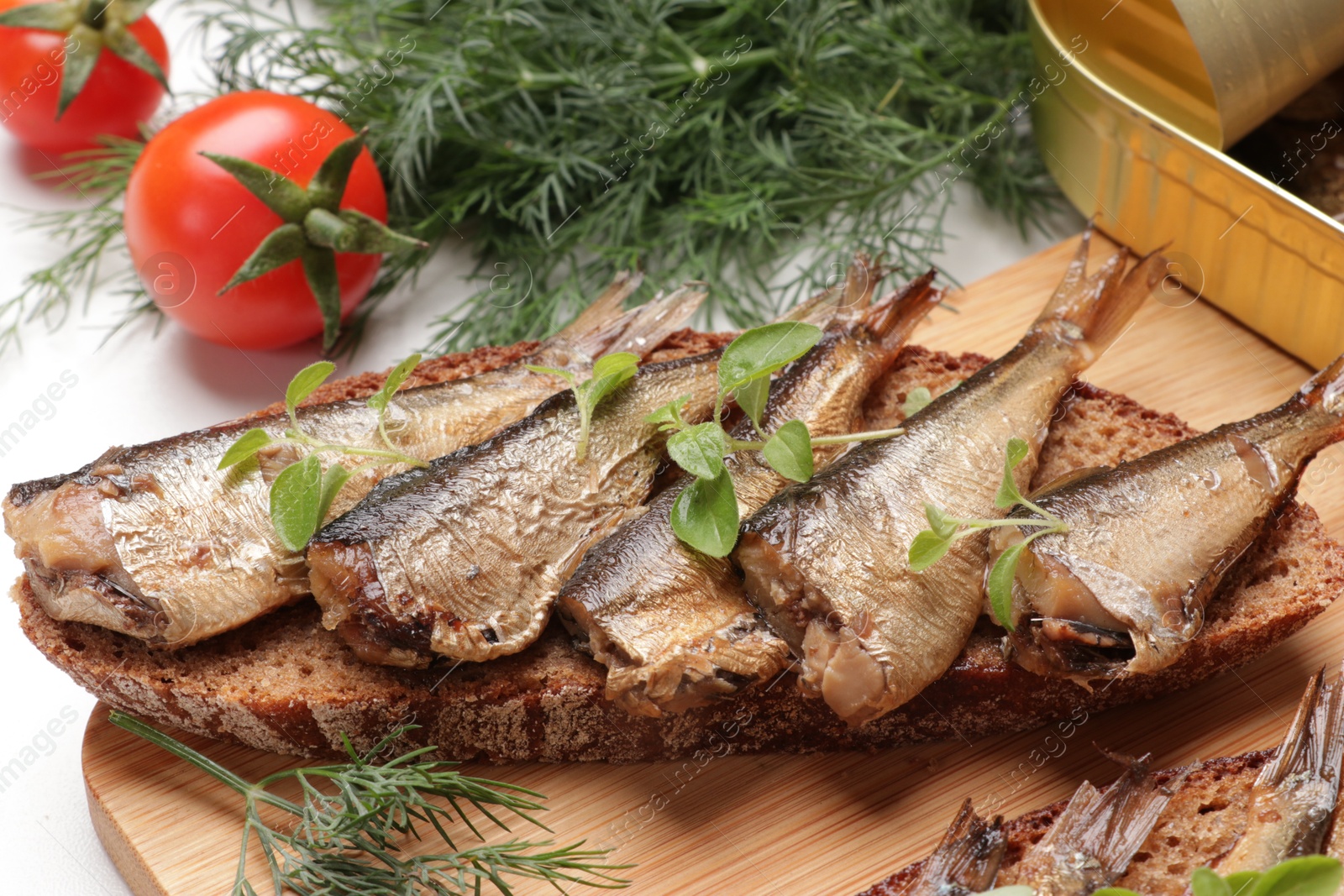 Photo of Delicious sandwich with sprats, dill and tomatoes on table, closeup