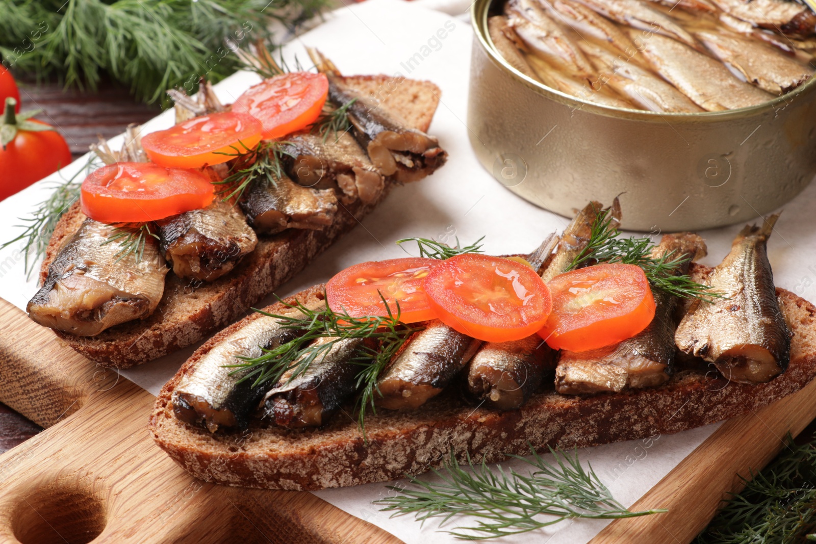 Photo of Delicious sandwiches with sprats, dill and tomato on table, closeup