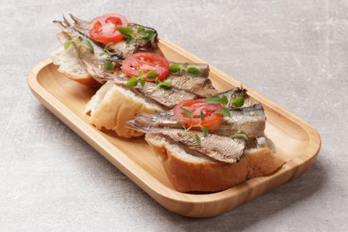 Delicious sandwiches with sprats, microgreens and tomato on grey table, closeup