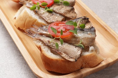 Photo of Delicious sandwiches with sprats, microgreens and tomato on grey table, closeup