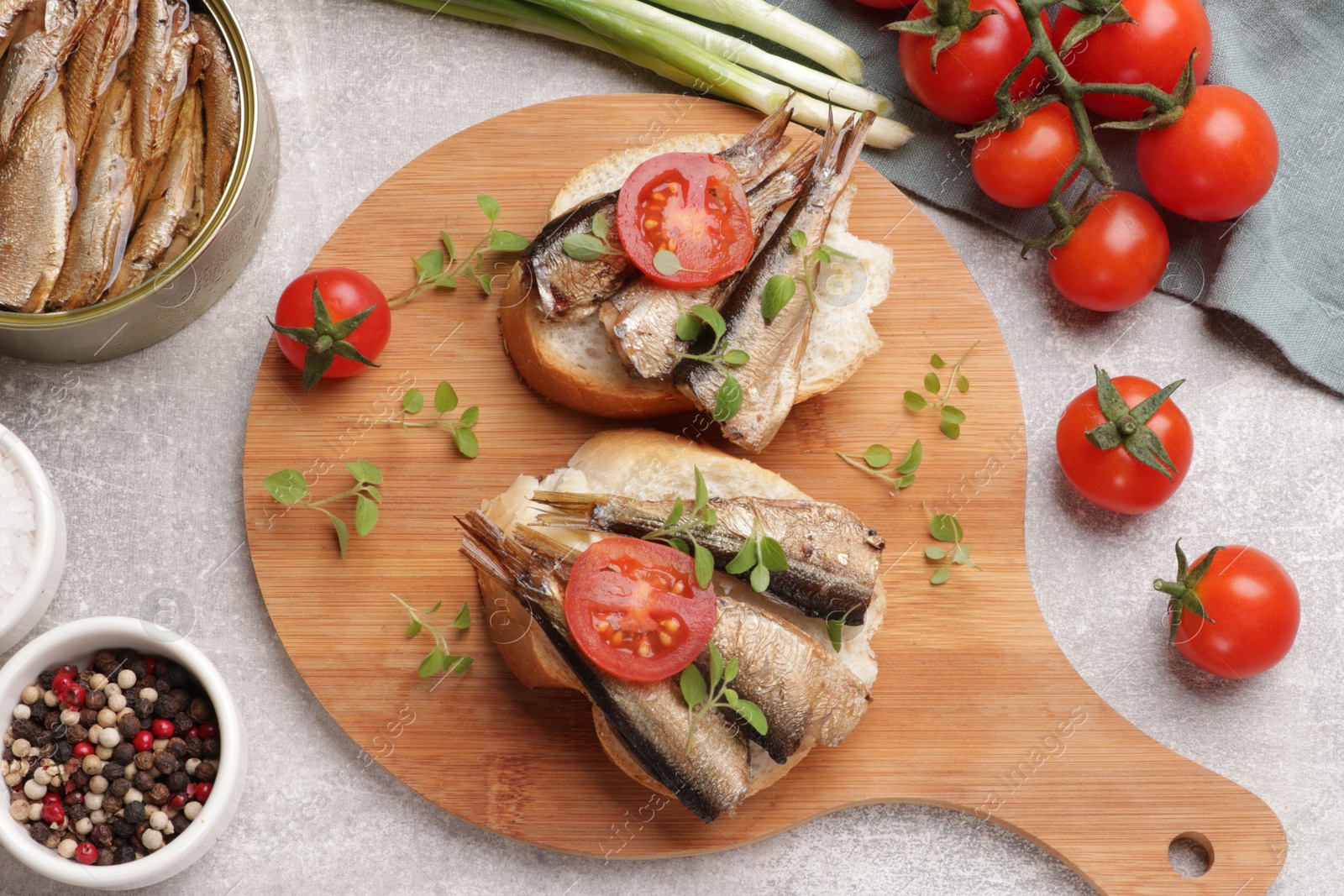 Photo of Delicious sandwiches with sprats served in grey table, top view