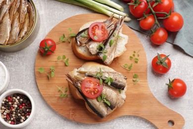 Photo of Delicious sandwiches with sprats served in grey table, top view