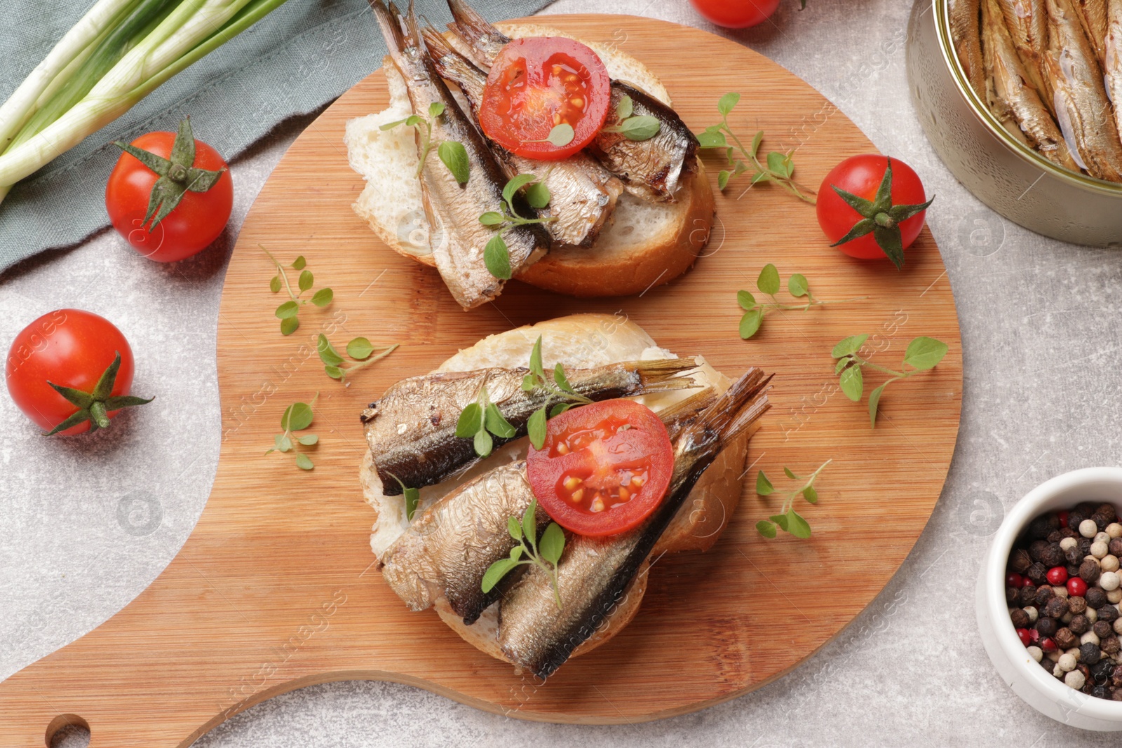 Photo of Delicious sandwiches with sprats served in grey table, top view