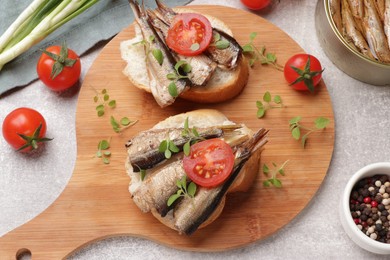 Photo of Delicious sandwiches with sprats served in grey table, top view