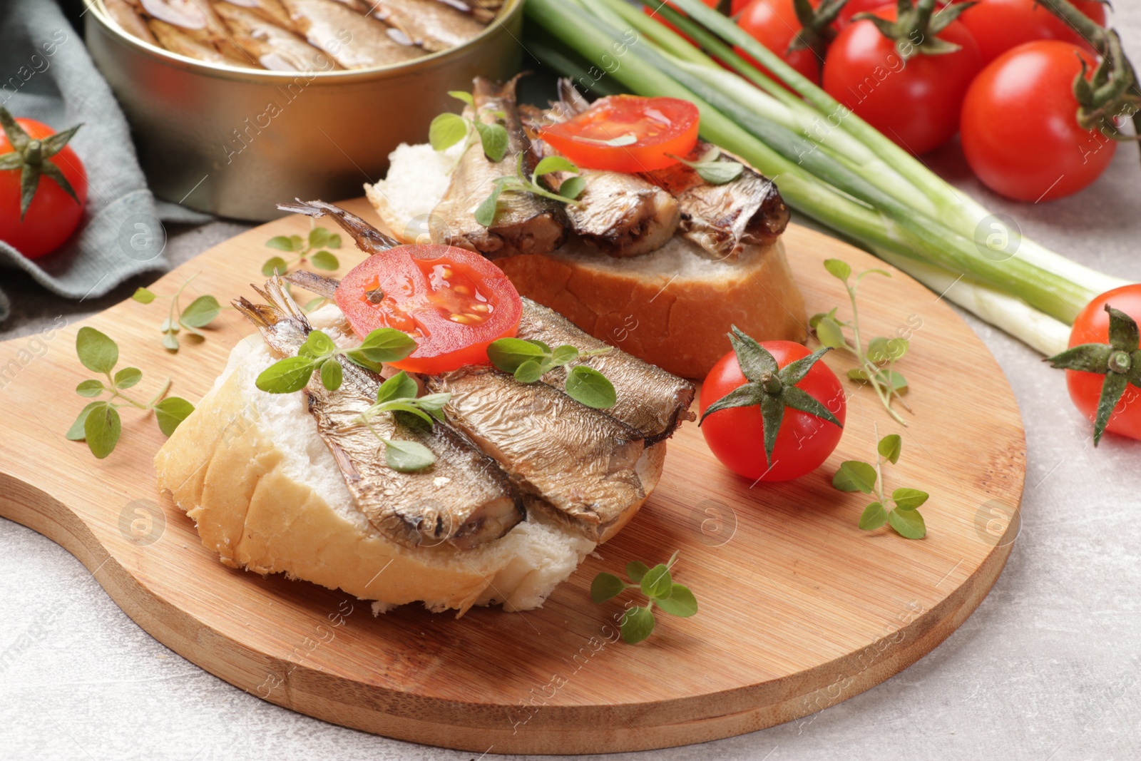 Photo of Delicious sandwiches with sprats, microgreens and tomato on grey table, closeup