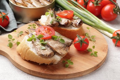 Delicious sandwiches with sprats, microgreens and tomato on grey table, closeup