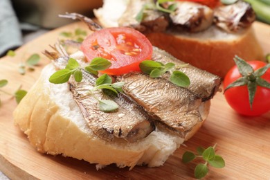 Photo of Delicious sandwiches with sprats, microgreens and tomatoes on table, closeup