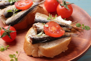 Delicious sandwiches with sprats, microgreens and tomatoes on table, closeup