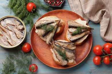 Photo of Delicious sandwiches with sprats and dill served on light blue wooden table, top view