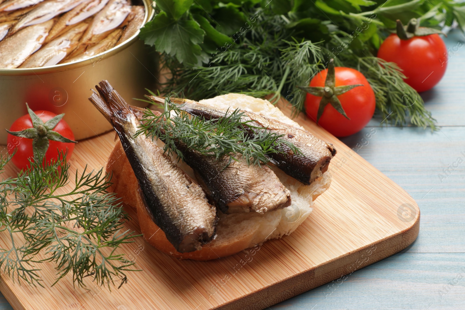 Photo of Delicious sandwich with sprats and dill served on light blue wooden table, closeup