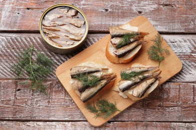 Photo of Delicious sandwiches with sprats and dill on wooden table, top view