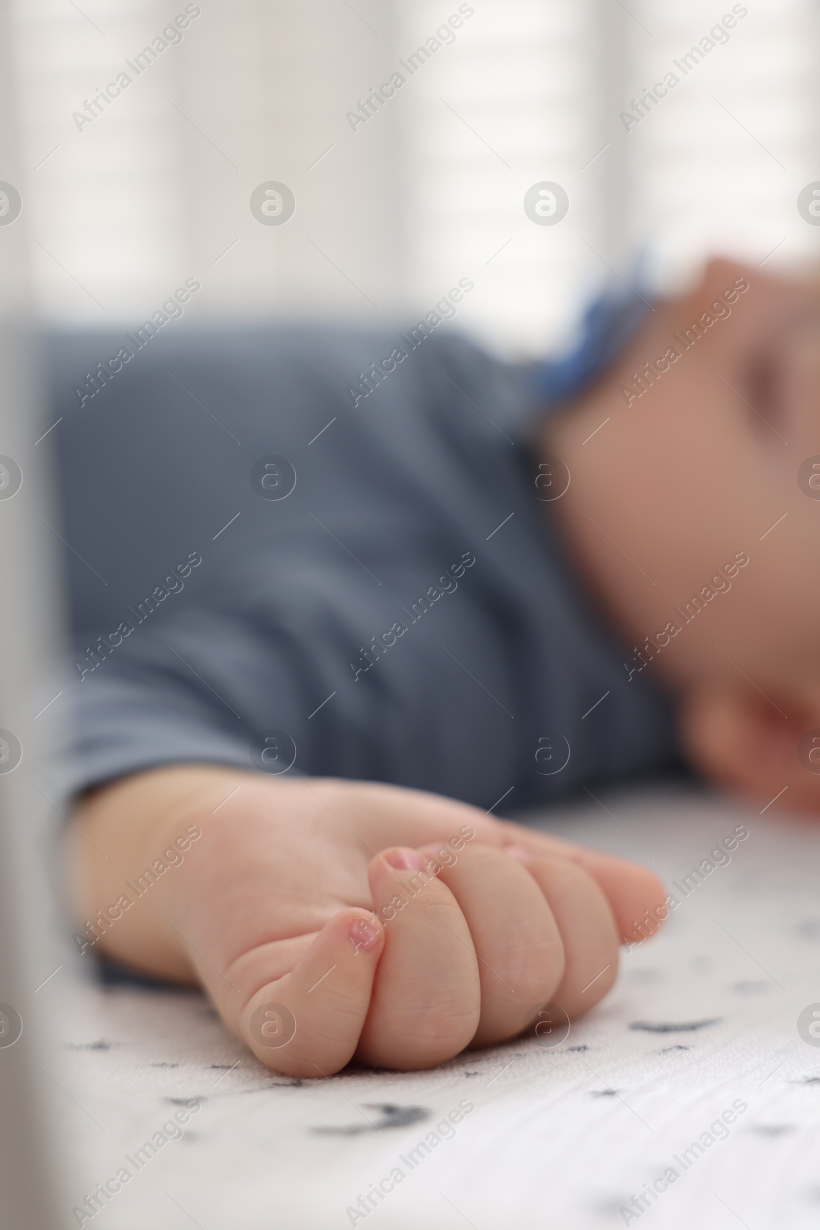 Photo of Cute baby sleeping in crib at home, closeup. Selective focus