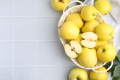 Photo of Fresh ripe yellow apples and leaves on white tiled table, flat lay. Space for text