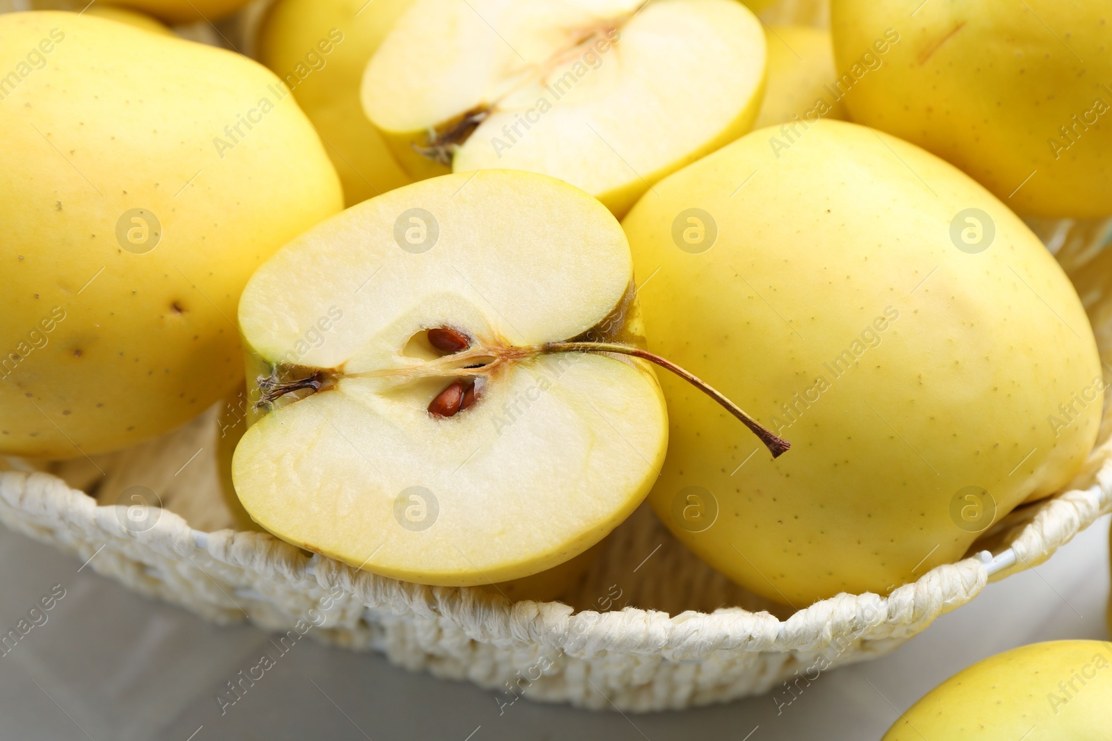 Photo of Fresh ripe yellow apples in basket on white table, closeup