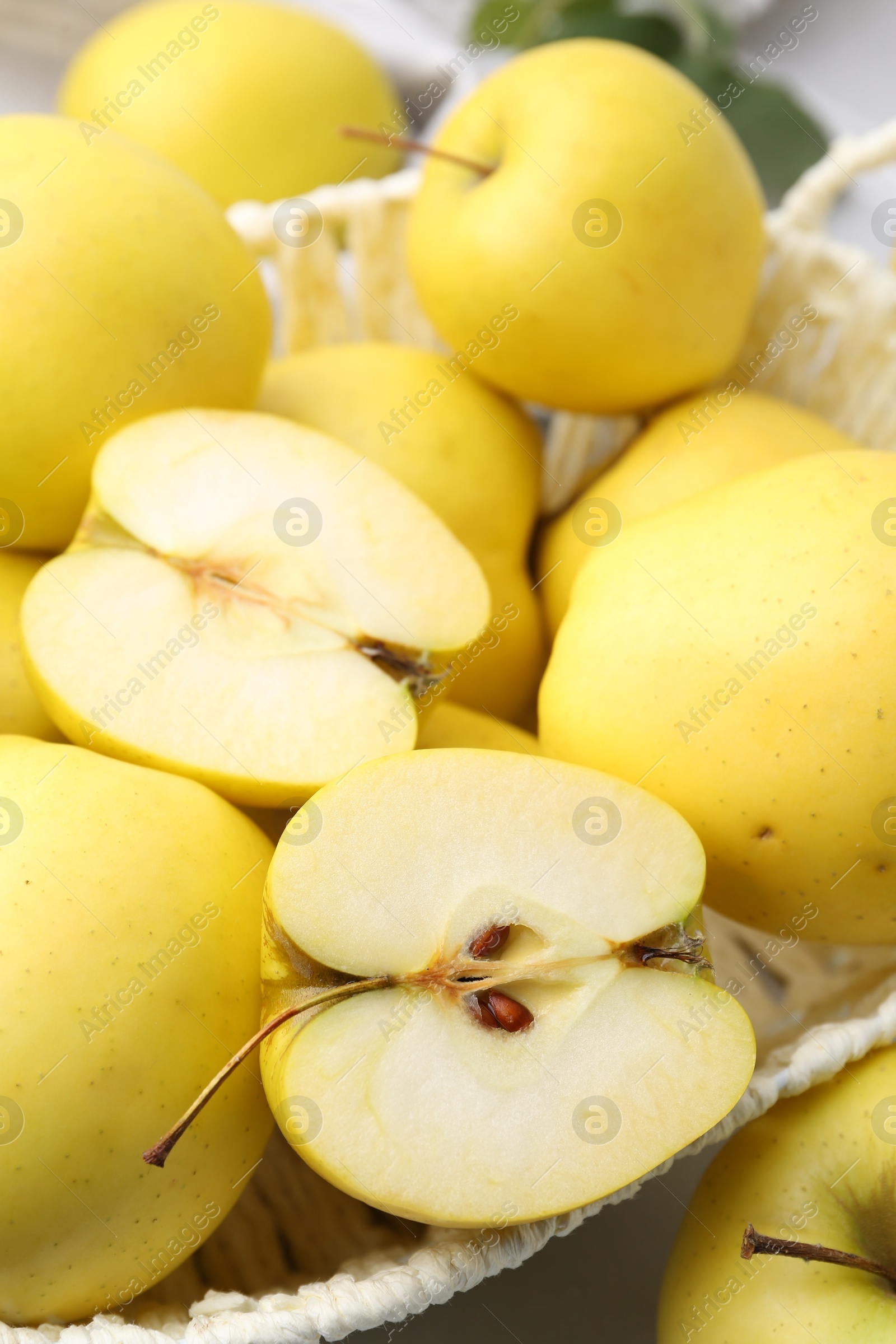 Photo of Fresh ripe yellow apples in basket on white table, closeup